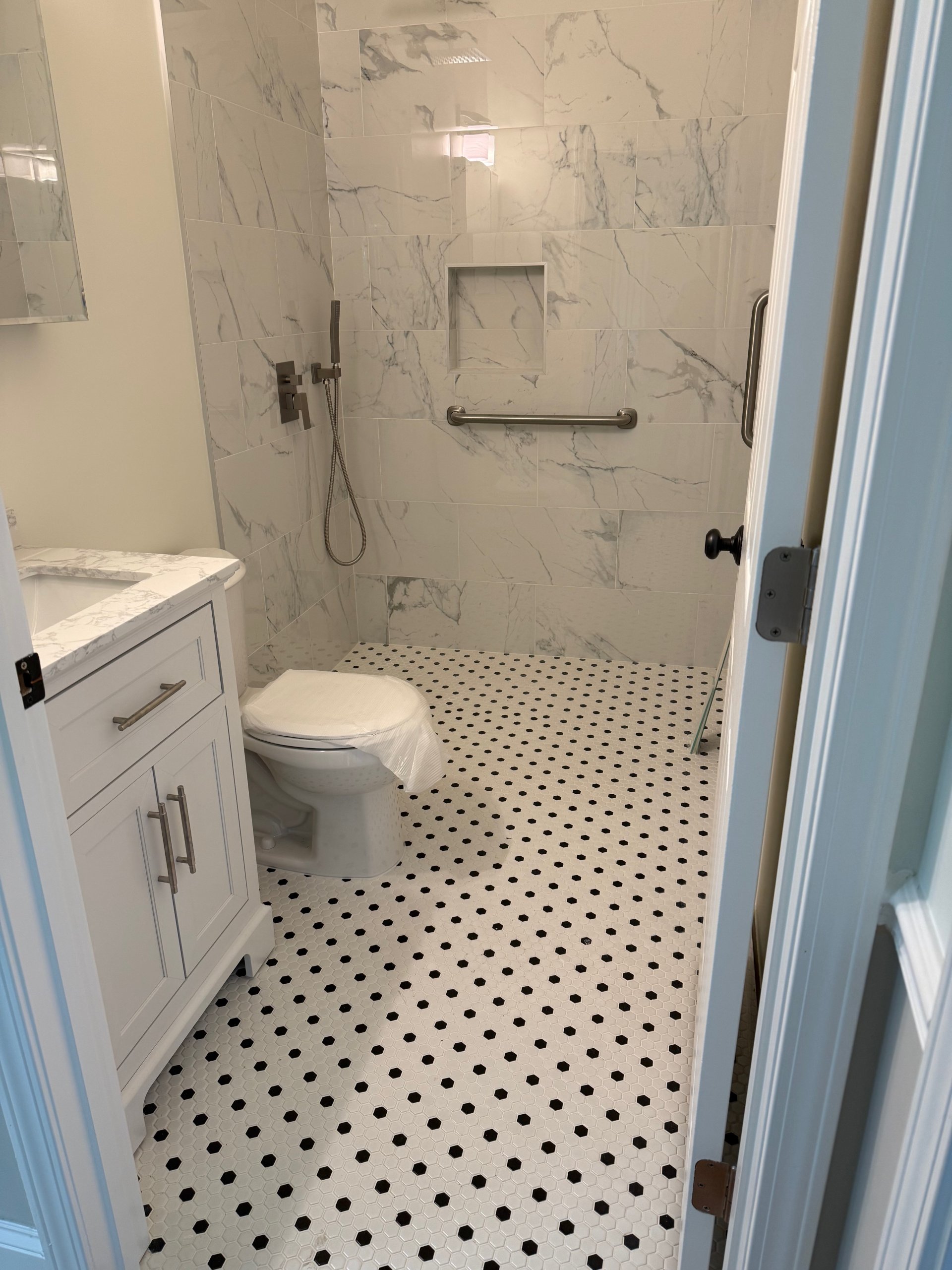 Remodeled bathroom with hex mosaic floor and marble-tile walk-in shower