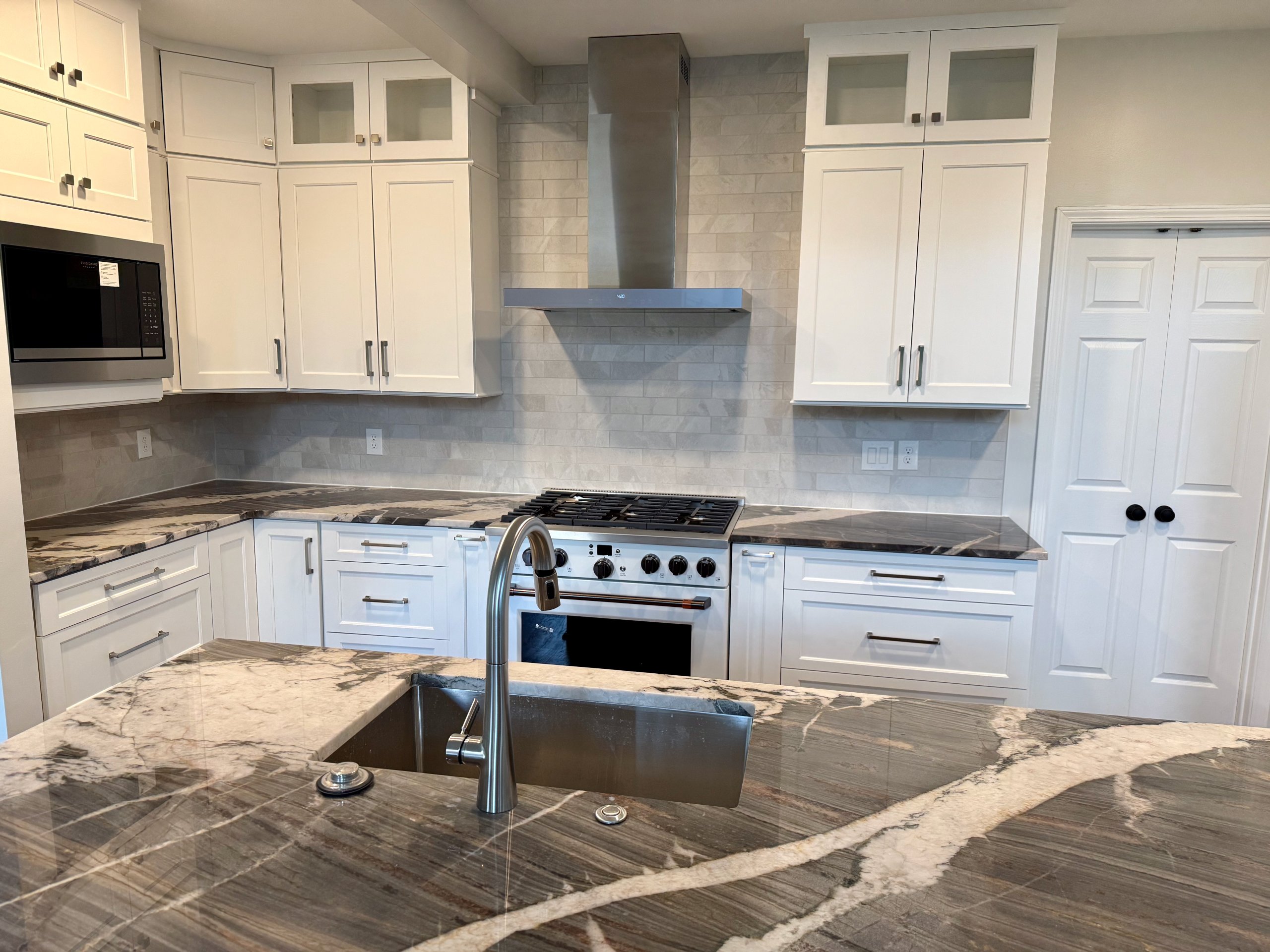 Finished kitchen remodel with white cabinets and quartzite counters