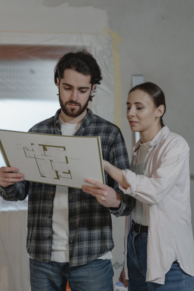 A couple examines a home renovation blueprint indoors, planning improvements together.