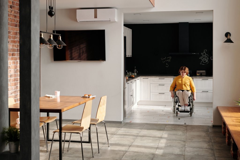 A woman in a wheelchair in a stylish, modern kitchen setting, emphasizing accessibility.