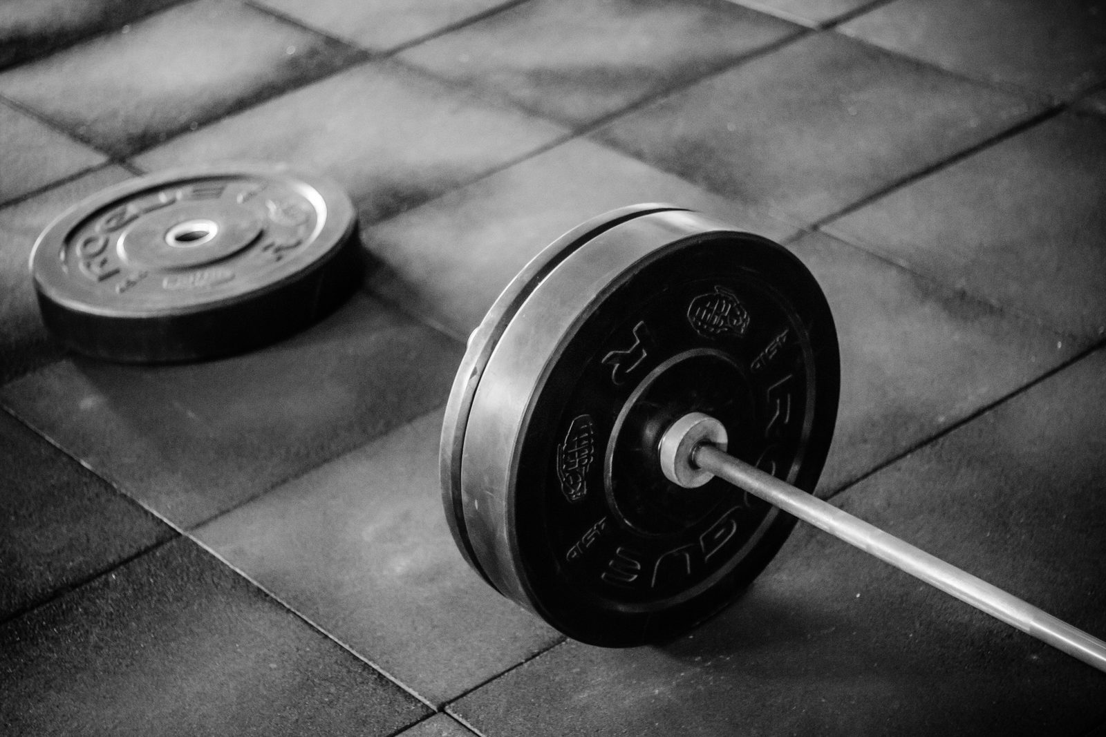 Heavy barbell and weights resting on rubber gym flooring