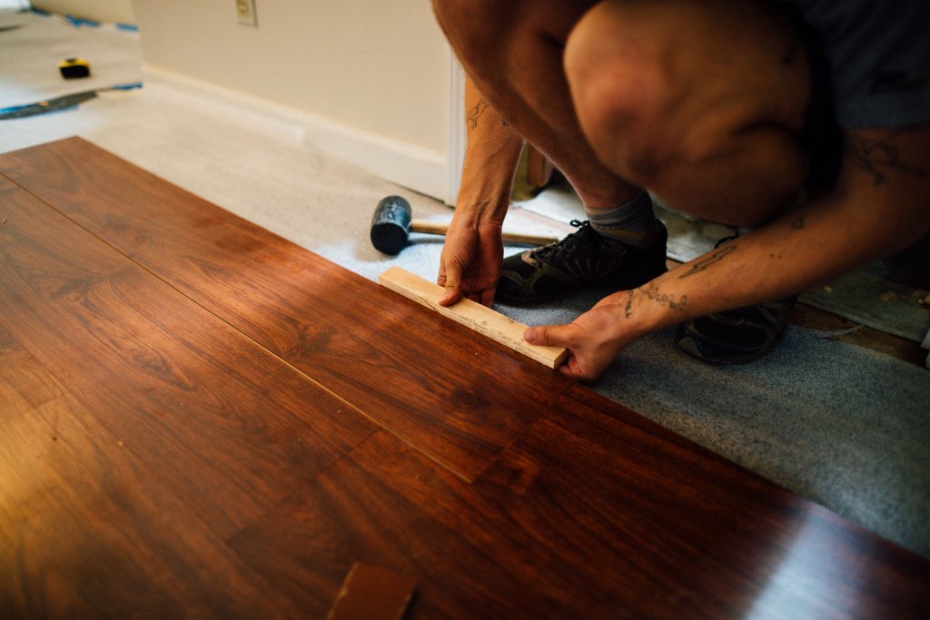 Installer laying laminate flooring during a renovation