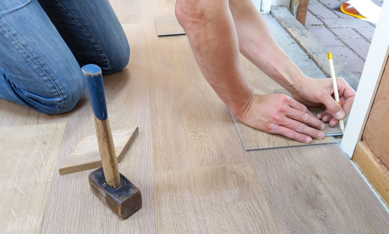 Installer measuring flooring planks before installation