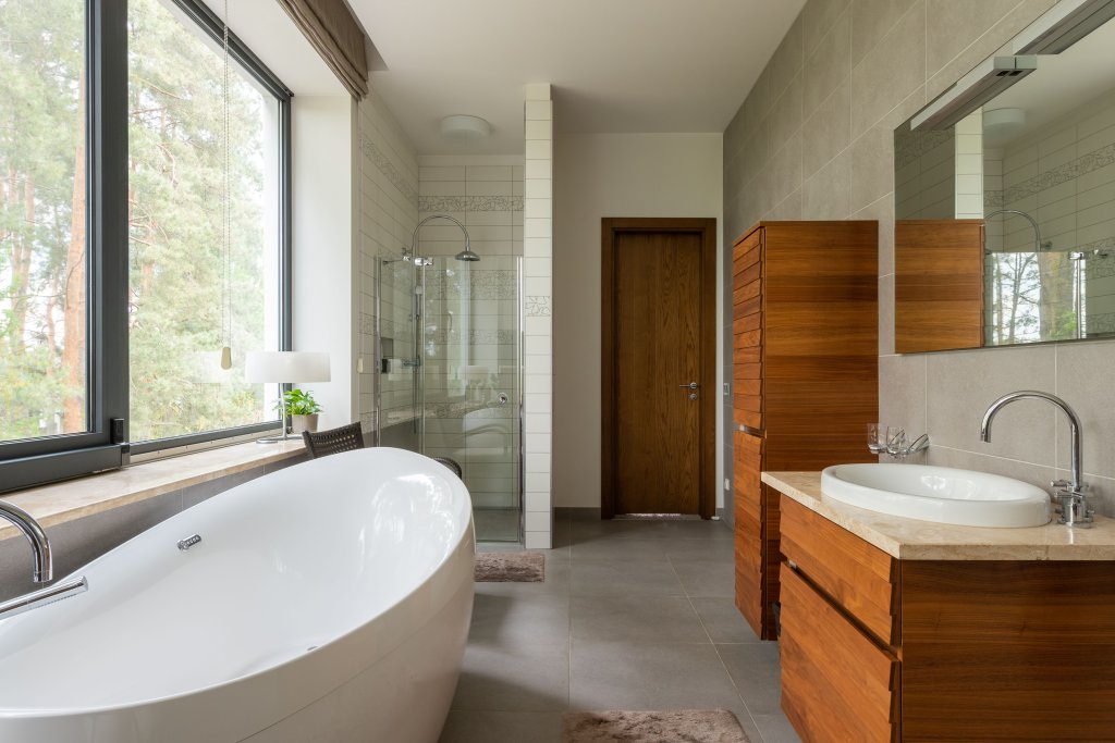 Interior of modern spacious bathroom with rectangular shaped mirror and glass shower cabin