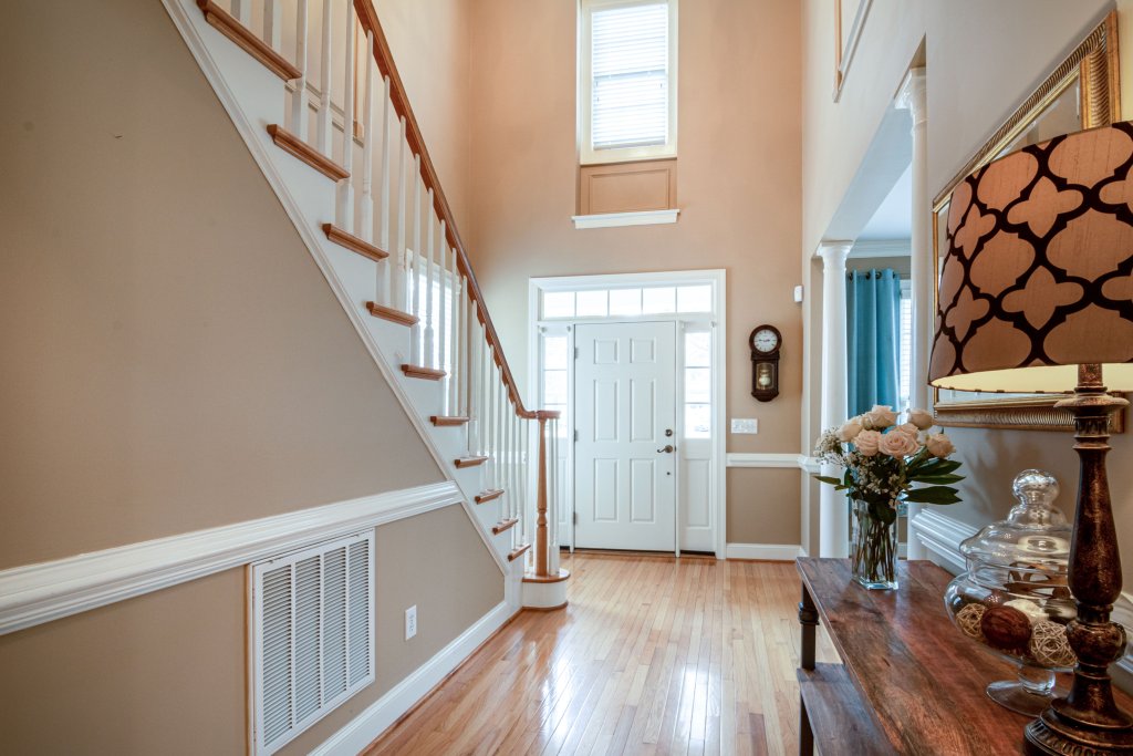 Sophisticated home entrance with staircase, wooden flooring, and elegant decor, showcasing modern interior design.
