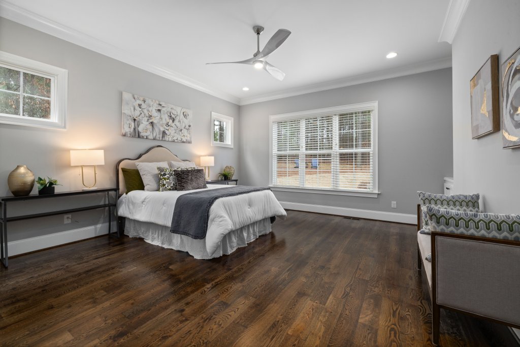 Spacious minimalist bedroom featuring hardwood floor and neutral decor.