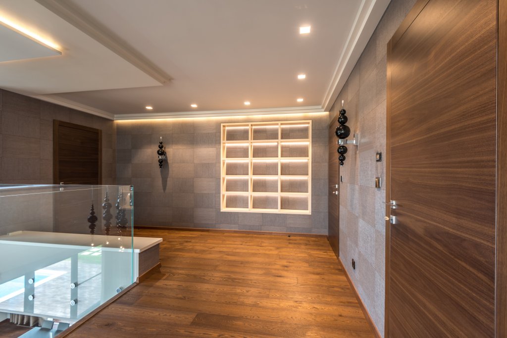 Spacious modern interior featuring wooden doors, flooring, and minimalistic design elements.