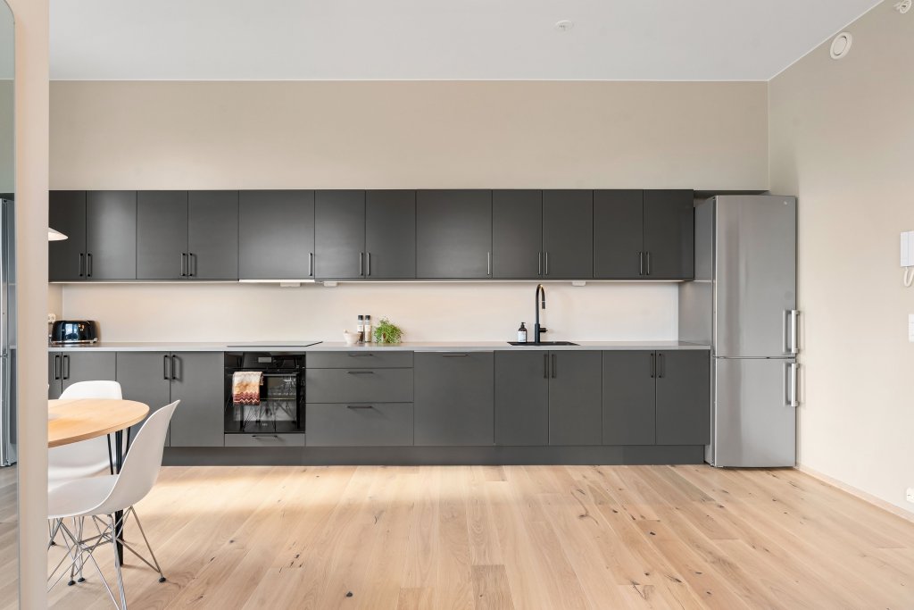 Spacious modern kitchen with sleek cabinets and wooden flooring, perfect for contemporary living.