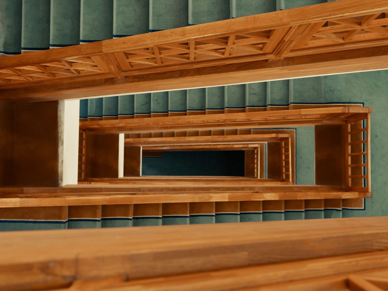 Wooden staircase with teal carpet viewed from above