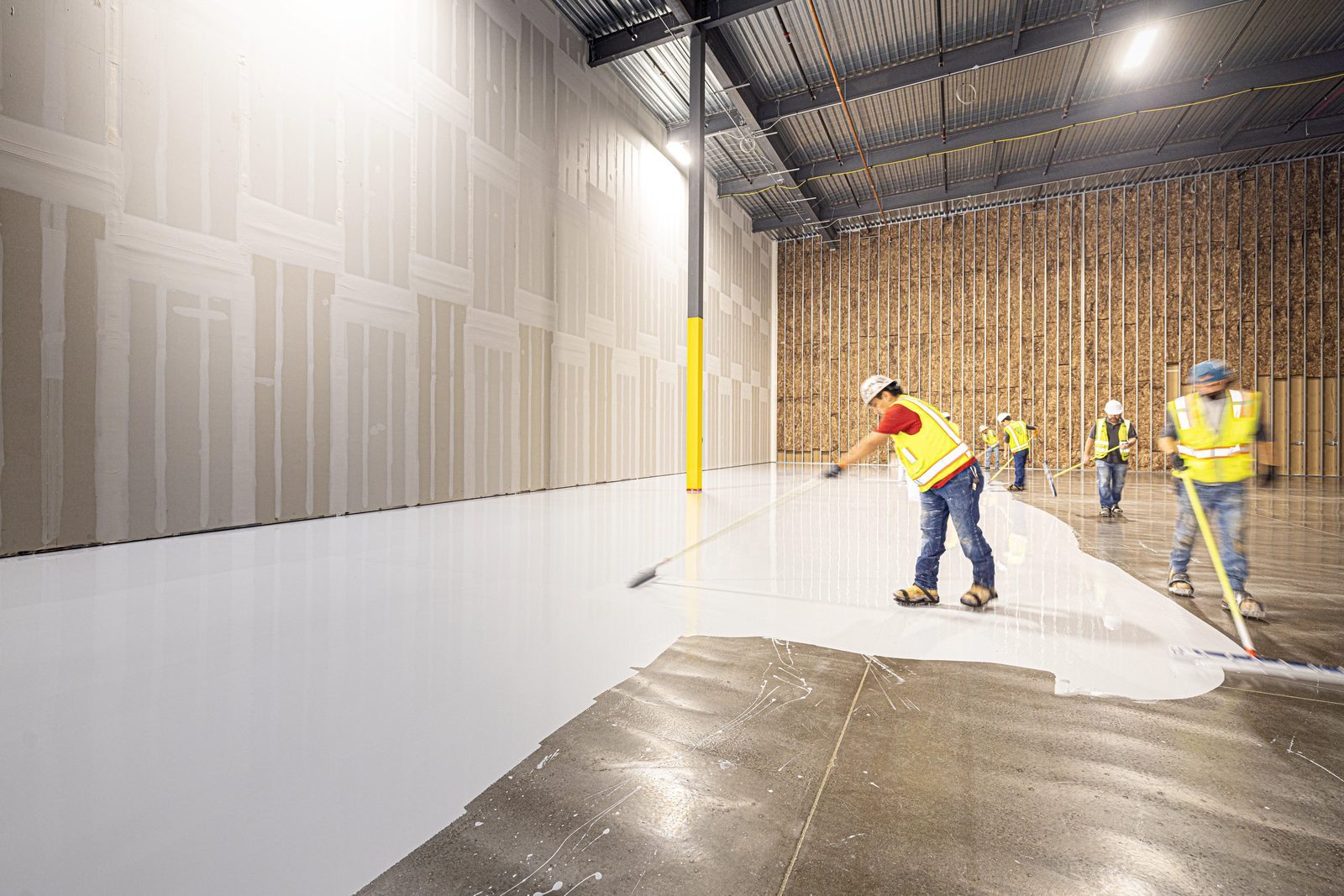 Workers preparing a concrete floor inside a building