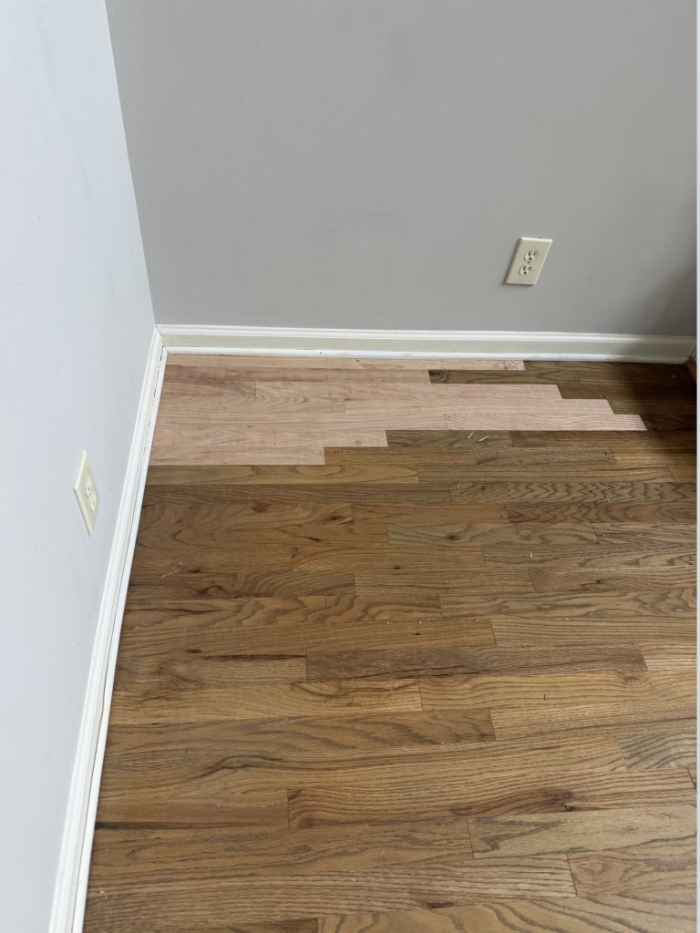 New red oak boards laced into an existing hardwood floor during a patch repair in a Cumming, GA home