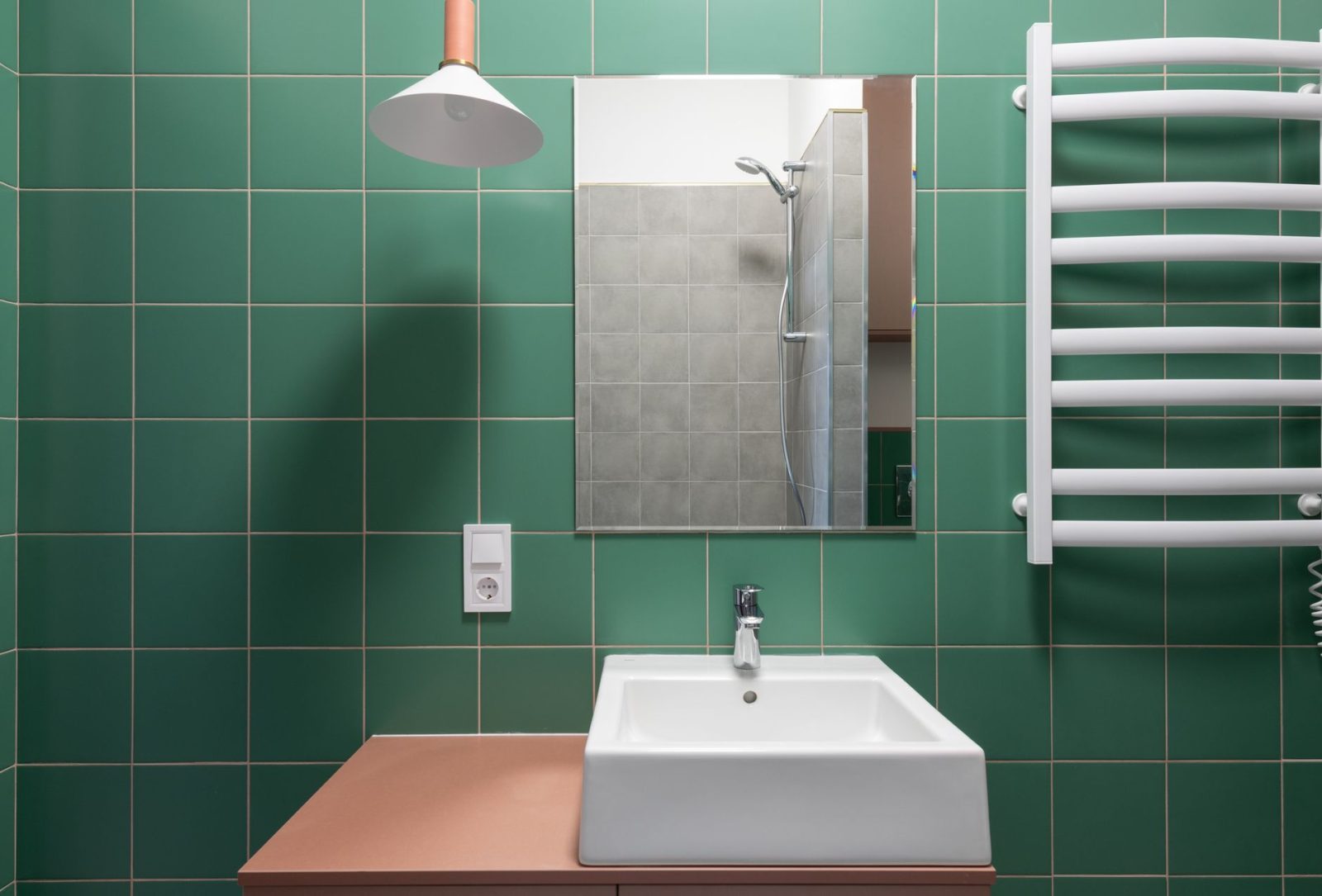 Tiled Cumming bathroom with green walls and a white ceramic sink